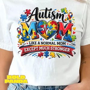 May include: White t-shirt with a colorful graphic design. The design features the words "Autism Mom" in a stylized font, with puzzle pieces and a heart-shaped element. The text "Like a normal mom except much stronger" is also included.