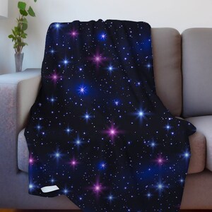 Puede incluir: Una manta suave y mullida con un fondo azul oscuro y un patr&oacute;n repetitivo de estrellas blancas, azules y rosas. Las estrellas son de diferentes tama&ntilde;os y tienen un efecto brillante.