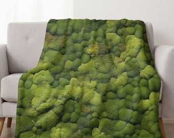 Puede incluir: Una manta de tiro verde musgo con un aspecto natural y texturizado. La manta está hecha de tela suave y felpa y es perfecta para agregar un toque de naturaleza a la decoración de tu hogar.