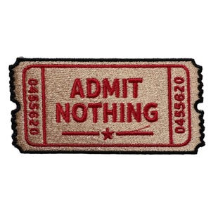 May include: A tan ticket-shaped patch with the words "ADMIT NOTHING" in red, along with a star and lines. The patch has a black border and the numbers "0455620" on each side.