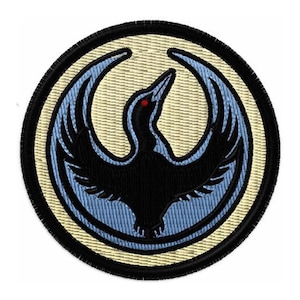 May include: Embroidered patch featuring a stylized black bird with outstretched wings, set against a light blue and cream-colored background. The bird has a red eye and is enclosed within a circular design with a black border. The patch is likely for clothing or accessories.