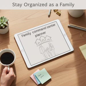 Könnte beinhalten: Ein weißes Tablet mit einer Grafik "Family Command Center Planner", mit einer Illustration von Familie und Haus. Das Tablet liegt auf einer Holzoberfläche, neben einer Tasse Kaffee, einer Sukkulente und Haftnotizen.
