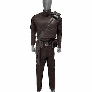 May include: Brown costume with a high collar, long sleeves, and matching pants. The outfit includes a shoulder bag, belt with pouches, and a strap across the chest. White stitching accents the seams. The costume is displayed on a mannequin.