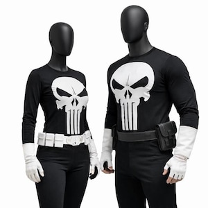 May include: Two mannequins dressed in black and white costumes. The outfits feature long-sleeved tops with a white skull design, black trousers, white gloves, and white boots. One costume has a white belt, the other a black belt with a pouch.