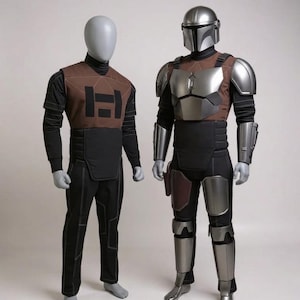May include: Two mannequins displaying costume sets. One wears a brown and black tactical-style outfit with a geometric chest emblem. The other wears a full suit of silver metallic armor, including a helmet, chest plate, shoulder guards, and leg armor.