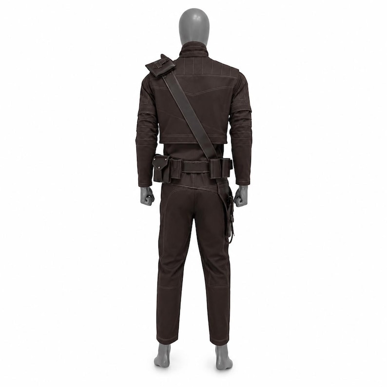 May include: Brown costume set on a mannequin. The outfit includes a jacket with shoulder strap, pants, and a belt with pouches. The jacket has a high collar and stitched details. The pants are straight-legged.