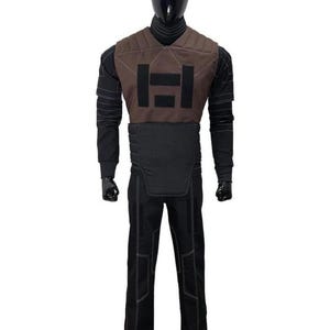 May include: A full-body costume displayed on a mannequin, featuring a brown chest piece with black rectangular patches, a black long-sleeved shirt with ribbed detailing, a black waist guard, and black trousers with visible white stitching throughout.