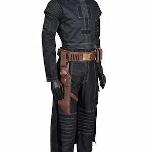 May include: Black costume with white stitching, featuring a long-sleeved top, pants, and a brown belt with a holster. The costume has a military-inspired design with padded details on the shoulders and knees. The belt has a gold-colored buckle.