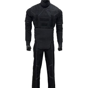 May include: Black tactical suit displayed on a mannequin. The suit includes a long-sleeved top with reinforced panels and white stitching, and matching pants. The mannequin is black, and the background is white.