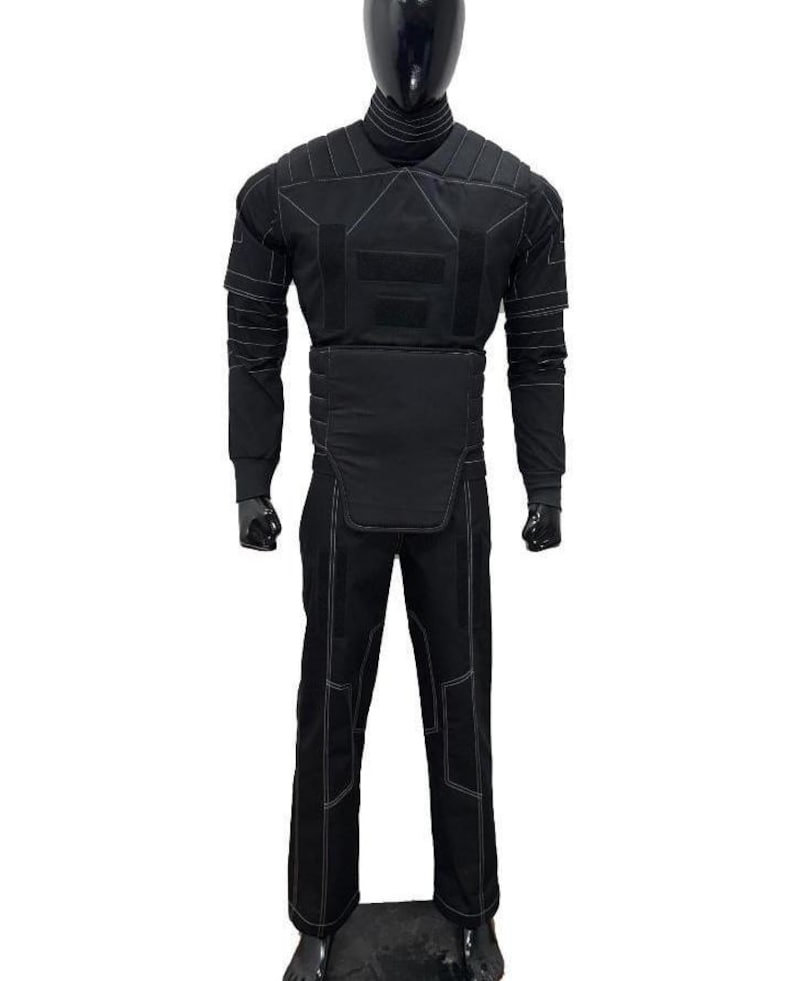 May include: Black tactical suit displayed on a mannequin. The suit includes a long-sleeved top with reinforced panels and white stitching, and matching pants. The mannequin is black, and the background is white.