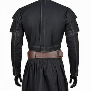 May include: Black costume with a cropped jacket featuring layered shoulder details and white stitching. A brown belt with multiple rectangular accents cinches the waist. The costume includes long sleeves and a pleated skirt.