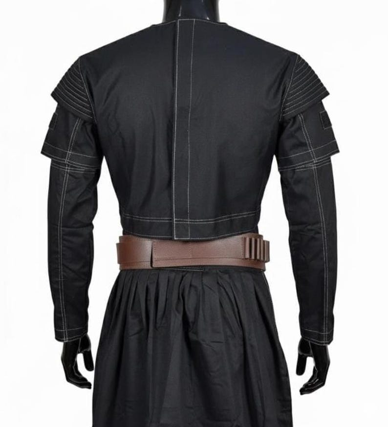 May include: Black costume with a cropped jacket featuring layered shoulder details and white stitching. A brown belt with multiple rectangular accents cinches the waist. The costume includes long sleeves and a pleated skirt.