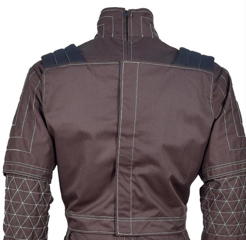 Op de afbeelding: Een donkerbruine jas met een hoge kraag met ritssluiting aan de achterkant, donkere schouderstukken en witte contraststiksels. De mouwen hebben een geometrisch driehoekig doorgestikt patroon en het achterpand heeft een verticale naad.