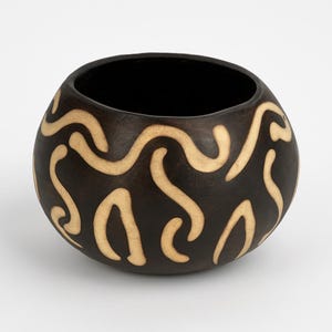 May include: A dark brown, round wooden bowl with a black interior. The exterior features a repeating pattern of light tan, wavy lines. The bowl has a smooth, polished finish and a simple, elegant design. This decorative bowl is suitable for various uses.