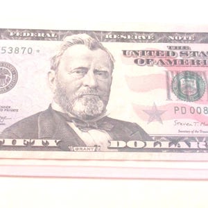 Op de afbeelding: Een biljet van vijftig dollar van de Amerikaanse Federal Reserve met een portret van Ulysses S. Grant in het midden. Het biljet toont de tekst Fifty Dollars, het getal 50 in de hoeken en het serienummer PD 00853870 met een stersymbool.
