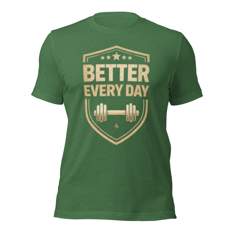 May include: Green t-shirt with a shield-shaped graphic in tan and white. The graphic features the text "BETTER EVERY DAY" above a barbell illustration. The shirt is made of a soft, textured fabric.