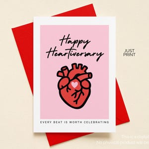 May include: A greeting card with a pink background and a red heart illustration. The card reads "Happy Heartiversary" in black script, with the phrase "Every beat is worth celebrating" below. The card is on a red envelope.