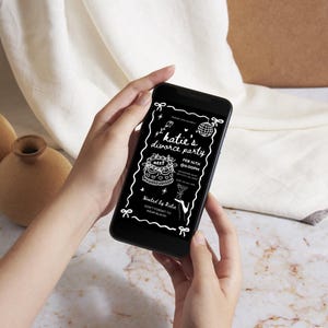 May include: A black smartphone displays a white invitation for "Katie's divorce party." The invitation includes a cake, disco ball, and martini glass illustrations. The text reads "Feb 14th 06:00PM" and "Don't forget to wear black."