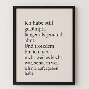 Könnte beinhalten: Ein gerahmter Druck mit schwarzem Rahmen. Der Druck zeigt schwarzen Text auf beigem Hintergrund. Der Text ist auf Deutsch und lautet: "Ich habe still gekämpft, länger als jemand ahnt. Und trotzdem bin ich hier - nicht weil es leicht war, sondern weil ich nie aufgegeben habe."