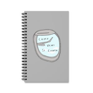 Può includere: Un taccuino grigio a spirale con un'illustrazione di un finestrino di un aereo. La finestra mostra un aereo in volo contro un cielo blu con nuvole. Il testo "COMU VENI SI CUNTA" è scritto all'interno della finestra.
