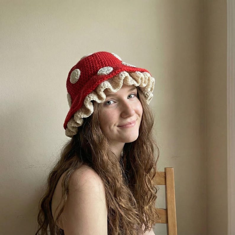 May include: A red crochet bucket hat with white polka dots and a ruffled beige brim. The hat is a whimsical accessory, perfect for adding a touch of fun to any outfit. The hat is a unique, handmade item.