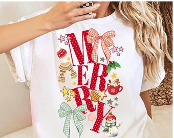 May include: A white t-shirt featuring the red text MERRY in a large, dotted font. The design includes a plaid bow, a red beanie, a striped scarf, a mug of hot cocoa, a gingerbread man, a snowman, and various stars in red, green, and pink.