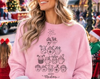 May include: A light pink long-sleeve sweatshirt featuring a black line art graphic of various mugs filled with hot beverages arranged in the shape of a Christmas tree, topped with a star, and the text Merry Christmas at the bottom.