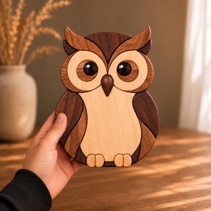 May include: A handcrafted wooden owl figurine composed of multiple interlocking pieces of light and dark wood. The owl features large, smooth black circular eyes, a pointed beak, and distinct layered wing patterns in contrasting wood tones.