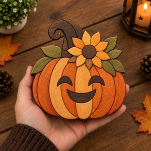 May include: A decorative wooden pumpkin ornament featuring a smiling face with dark brown eyes and a mouth. The pumpkin is crafted from segments of light and dark orange wood, topped with a dark brown stem, green leaves, and a yellow sunflower.