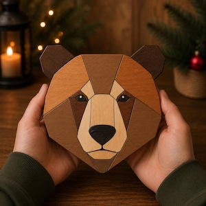 May include: A geometric wooden bear head wall art piece constructed from various shades of brown, tan, and cream wood segments. The design features a dark brown nose, almond-shaped eyes, and pointed ears, assembled in a mosaic-like pattern.