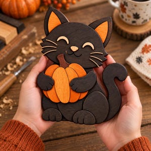 May include: A handcrafted wooden cutout of a black cat with orange inner ears and a small nose, holding a bright orange pumpkin. The cat has a smiling expression with closed eyes and whiskers, featuring layered wood pieces with visible grain.