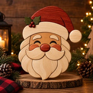 Peut inclure: Une décoration en bois représentant un visage de Père Noël avec un bonnet rouge à bordure blanche et pompon, une barbe claire, un nez rouge rond et des feuilles de houx vertes avec des baies rouges. L'objet est fait de segments de bois superposés.