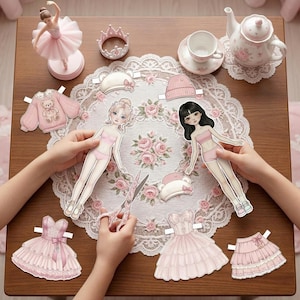 Coquette and Balletcore paper doll collection on a desk. Features lace dresses, pink bows, and ballet slippers. A silk ribbon and pearl necklace are placed next to the A4 printables. Part of a 120-page mega bundle with pre-fitted outfits for nostalgic adults and creative journaling.