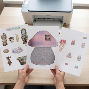 May include: Three printed sheets featuring a paper doll set titled Fairy Bathroom. The sheets include a mushroom-shaped room backdrop with patterned walls, various bathroom furniture stickers, a fairy character, and several clothing items.
