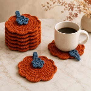 Può includere: Una pila di sottobicchieri rotondi all'uncinetto color arancione con bordi smerlati, ognuno caratterizzato da un piccolo dettaglio a forma di fiore e stelo blu. Un sottobicchiere è appoggiato in piano e un altro sostiene una tazza in ceramica.