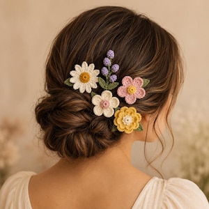Puede incluir: Un conjunto de accesorios para el cabello de ganchillo que incluye una margarita blanca con centro amarillo, una ramita de lavanda morada, una pequeña flor crema con centro rosa, una flor rosa con centro amarillo y una flor amarilla con centro blanco.
