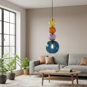 May include: A contemporary pendant light with a cluster of coloured glass spheres. The light fitting has a large blue globe at the base, with purple, orange, and yellow spheres above. It hangs from a black cable with a gold-coloured ceiling fixture.