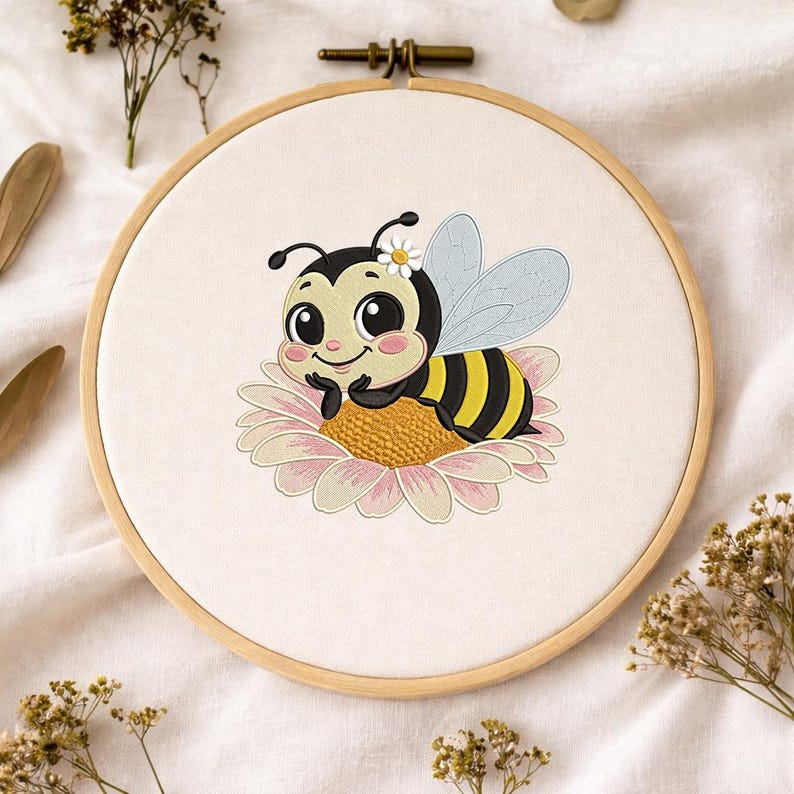 May include: A charming embroidery hoop featuring a cartoon bee resting on a daisy. The bee has black and yellow stripes, a white flower, and light blue wings. The daisy is pink and yellow, set against a white fabric background, within a wooden hoop.