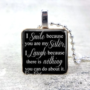 May include: Black square pendant necklace with a silver chain. The pendant has white text that reads "I Smile because you are my Sister, I Laugh because there is nothing you can do about it."