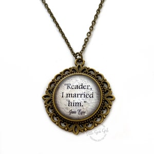 Op de afbeelding: Een bronzen ketting met een ronde hanger met de quote "Reader, I married him." van Jane Eyre. De hanger heeft een decoratief filigraanontwerp.