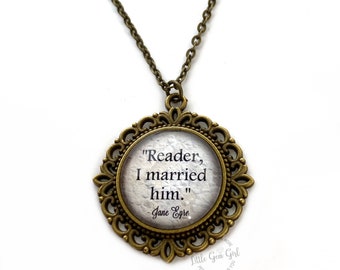May include: A bronze necklace with a round pendant featuring the quote "Reader, I married him." by Jane Eyre. The pendant has a decorative filigree design.