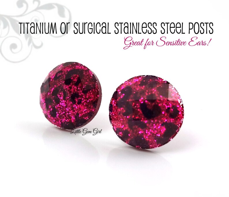 May include: A pair of pink glitter stud earrings with a black leopard print design. The earrings are made with titanium or surgical stainless steel posts, which are great for sensitive ears.