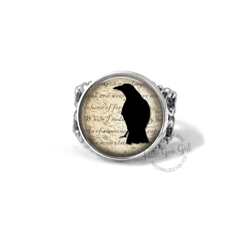 Pu&ograve; includere: Un anello d'argento con una silhouette di corvo nero su uno sfondo di carta vintage. L'anello presenta un cabochon rotondo di vetro con una silhouette di corvo nero su uno sfondo di carta vintage. Il testo sulla carta recita "upon a dmy weak and wear volume of for While I nodo As of someone Tis some visi and in".