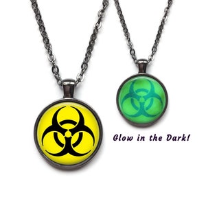 May include: A black chain necklace with a round pendant featuring a yellow biohazard symbol. The pendant glows in the dark and is green when illuminated.