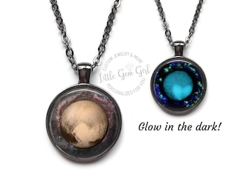 May include: Two necklaces with round glass pendants. One pendant features a photo of Pluto, the other pendant glows in the dark and features a blue and green nebula. The necklaces are on a white background.  "Custom Jewelry & More Little Gem Girl Personalized for You" is written on a circle in the background.