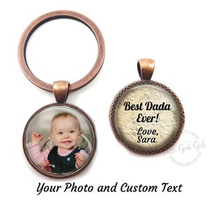 May include: A copper-toned keychain with a round photo charm and a round charm with the text "Best Dada Ever! Love, Sara".