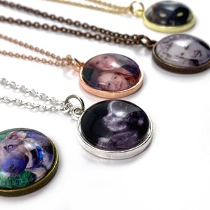 Puede incluir: Cinco collares con colgantes redondos de vidrio que muestran diferentes fotos. Los colgantes est&aacute;n unidos a cadenas plateadas, doradas y de bronce.