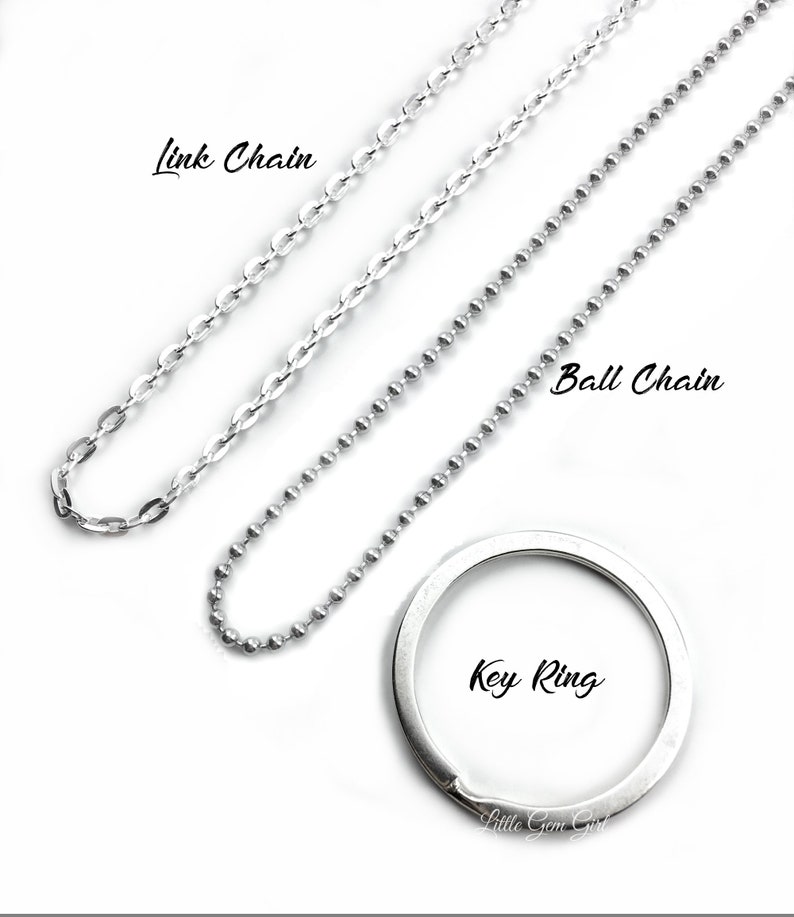 May include: Three silver chains, a link chain, a ball chain, and a key ring. The chains are laid out on a white background.