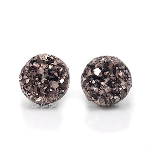 May include: A pair of small, round, brown and gold stud earrings with a sparkly, textured surface.