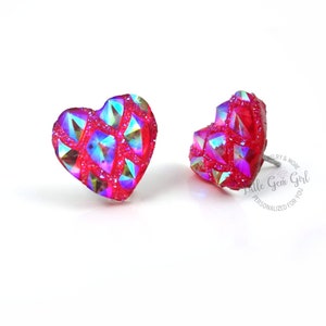May include: A pair of heart-shaped earrings with a red glitter finish and iridescent accents.
